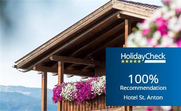 Wooden balcony with floral decorations and HolidayCheck award “100% recommendation” for Hotel St. Anton.