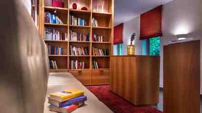 Leseecke mit Bücherregal, Sofa, Stehlampe und warmen Holzelementen.