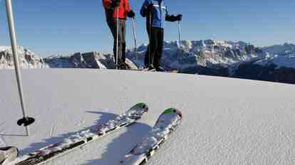 Sciatore su una pista da sci davanti a un paesaggio montano innevato.