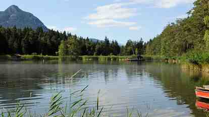 The Völser Weiher surrounded by forest and mountain scenery.