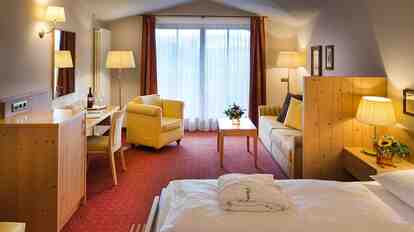 Doppelzimmer Charme St. Peter mit Holzkopfteil, Schreibtisch, Sitzbereich und Balkon.