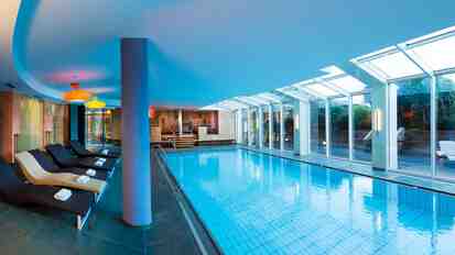 Hallenbad im Hotel St. Anton mit Liegen, Glasfront, Sauna- und Ruhebereich.