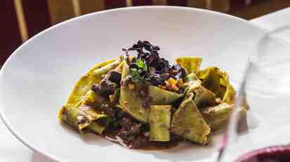 Tagliatelle with meat ragout and sprouts on a white plate.