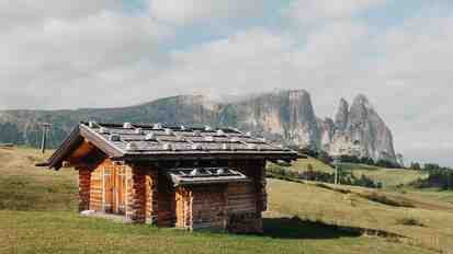 Holzhütte auf der Seiser Alm; im Hintergrund die markante Bergkulisse des Schlerns.