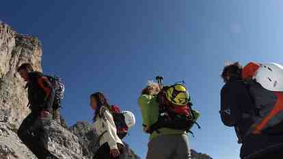 Four hikers with climbing equipment in an imposing mountain range.