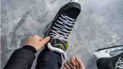 Close-up of an ice skate on the ice being laced up.